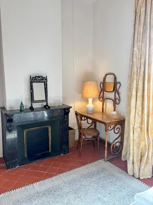 a living room with a fireplace and a table with a lamp at Château de Gragnos in Saint-Chinian
