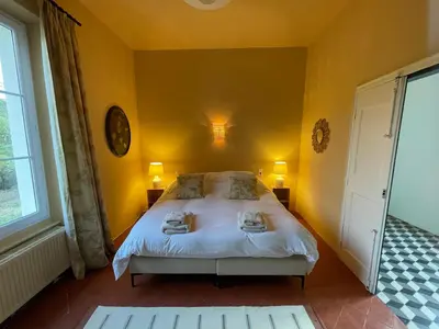 a bedroom with a large bed with yellow walls at Château de Gragnos in Saint-Chinian