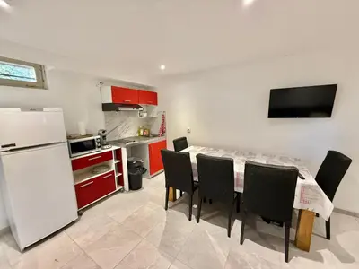 a kitchen with a table and chairs and a white refrigerator at Logement en souplexe indépendant dans une propriété in Castres