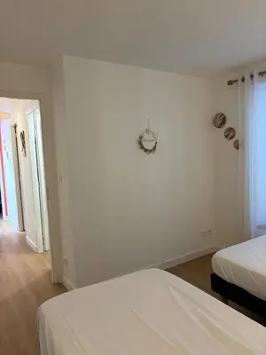 a white bedroom with two beds and a clock on the wall at L'étoile des remparts in Lagrasse
