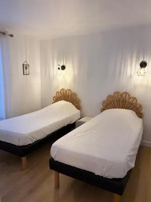 two beds in a room with white sheets and lights at L'étoile des remparts in Lagrasse