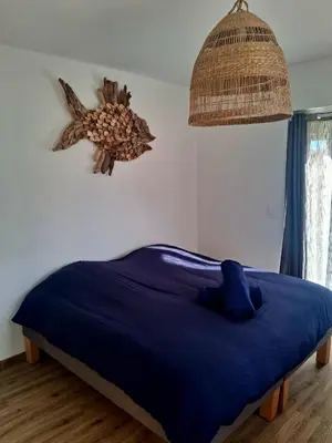 a bedroom with a bed with a blue blanket and a fan at Le Repaire Secret, studio cosy et calme Narbonne in Narbonne
