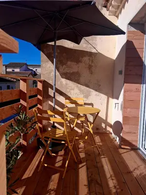 a table and chairs on a deck with an umbrella at Le Repaire Secret, studio cosy et calme Narbonne in Narbonne