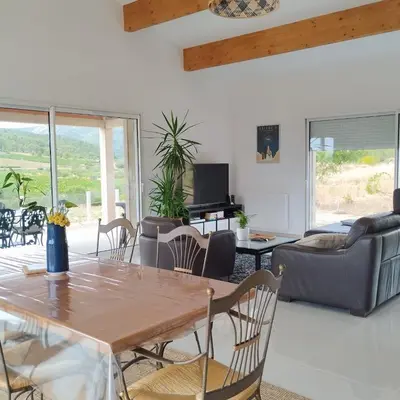 a living room with a wooden table and chairs at Villa with private pool and panoramic view in Félines-Minervois