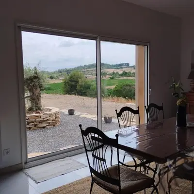 a dining room with a table and chairs and a large window at Villa with private pool and panoramic view in Félines-Minervois