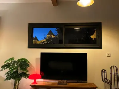 a flat screen tv hanging on a wall with a table at Le jardin de la Vade in Carcassonne