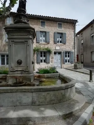 a water fountain in front of a building at La maison de la fontaine in Villeneuve-Minervois