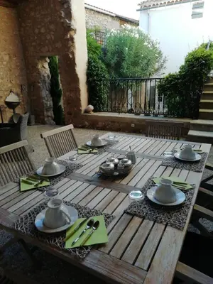 a wooden table with utensils on top of it at La maison de la fontaine in Villeneuve-Minervois