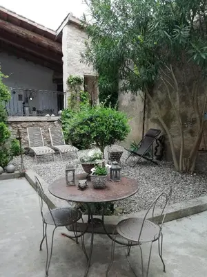 a patio with a table and chairs in a yard at La maison de la fontaine in Villeneuve-Minervois