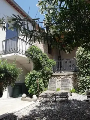 a house with a gate and chairs in a courtyard at La maison de la fontaine in Villeneuve-Minervois