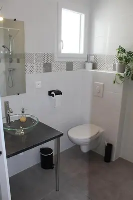 a white bathroom with a toilet and a sink at Villa la garrigue in Boutenac