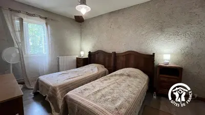 a bedroom with two beds and a table and a window at Chateau st-auriol - le caviste in Lagrasse