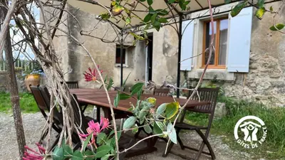 a wooden picnic table in front of a house with flowers at Chateau st-auriol - le caviste in Lagrasse