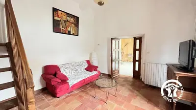 a living room with a red couch and a tv at Chateau st-auriol - le caviste in Lagrasse