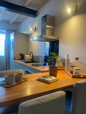 a kitchen with a wooden table with chairs and a counter at Petite maison au centre de Mirepoix in Mirepoix
