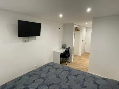 a bedroom with a bed and a desk with a television on the wall at Maison de ville rénovée - Carc'apparts - terrasse in Carcassonne