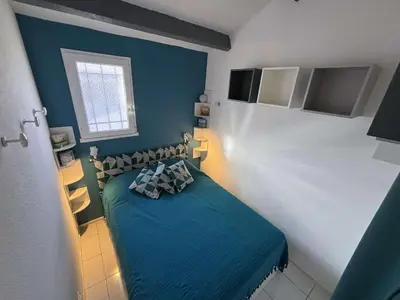 a small bedroom with a blue bed and a window at Appartement Studio Cabine Mezzanine 4 couchages- PORT-LA NOUVELLE PN290-031 in Port-la-Nouvelle
