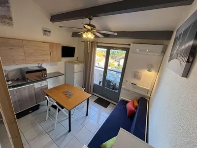 a small kitchen with a blue couch and a table at Appartement Studio Cabine Mezzanine 4 couchages- PORT-LA NOUVELLE PN290-031 in Port-la-Nouvelle