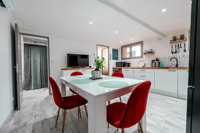 a kitchen with a white table and red chairs at Darja in Carcassonne