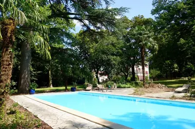 a blue swimming pool in a park with trees at Gite Charles de Castres in Saint-Affrique-les-Montagnes