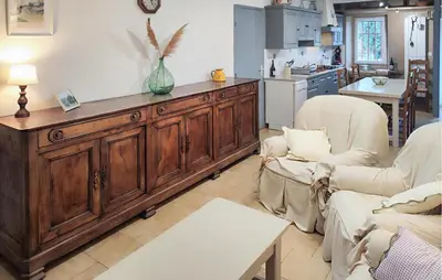 a living room with a large wooden cabinet and two chairs at 2 Bedroom Awesome Home In Pardailhan in Pardailhan