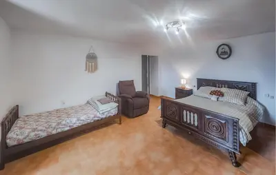 a bedroom with a bed and a couch and a chair at 2 Bedroom Awesome Home In Pardailhan in Pardailhan