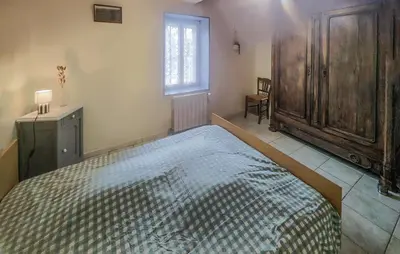 a bedroom with a bed and a dresser and a window at 2 Bedroom Awesome Home In Pardailhan in Pardailhan