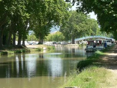 a boat is docked on a river with a bridge at Relaxing Retreat Near Minerve in Aigne