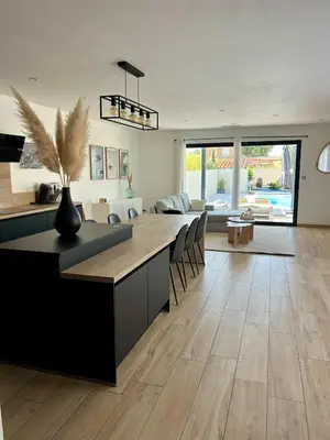 a kitchen with a dining table and a living room at La villa du soleil in Lapalme