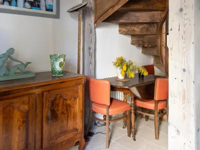 a dining room with a wooden table and orange chairs at D'une maison à l'autre in Cépie