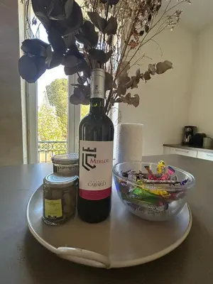 a bottle of wine and a bowl of flowers on a table at L'Escapade Narbonnaise in Narbonne