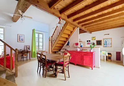 a kitchen and dining room with a table and red cabinets at La Maison Bleue de Sigean - Loft 1 in Sigean