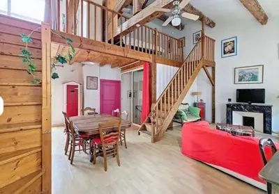 a living room with a table and a red couch at La Maison Bleue de Sigean - Loft 1 in Sigean