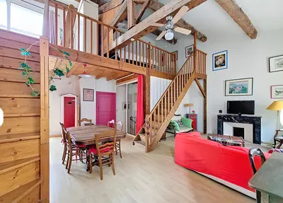a living room with a table and a red couch at La Maison Bleue de Sigean - Loft 2 in Sigean