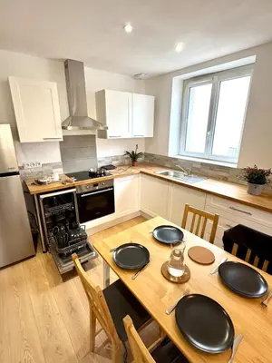 a kitchen with a wooden table with chairs and a kitchen with a stove at Saint-Germain T2 Residence Apartment in Carcassonne