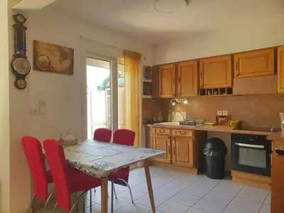 a kitchen with a table and some red chairs at Maison confortable à Carcassonne avec jardin privé in Carcassonne