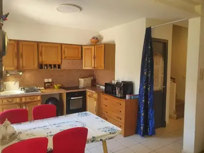 a kitchen with wooden cabinets and a table with red chairs at Maison confortable à Carcassonne avec jardin privé in Carcassonne