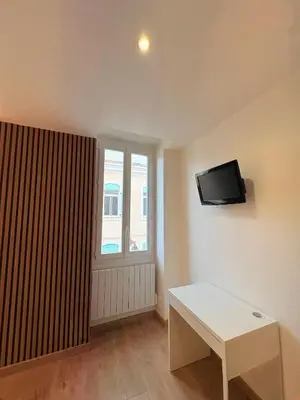 a living room with a table and a tv on the wall at L'Atelier Bohème - Studio élégant en centre ville in Pamiers