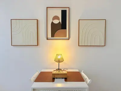 a table with a lamp in a room with three pictures at L'Atelier Bohème - Studio élégant en centre ville in Pamiers