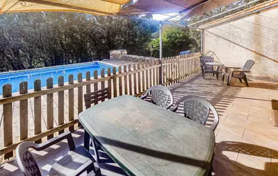 a wooden table and chairs on a deck with a pool at Pause Nature Avec Piscine in Ferrières-Poussarou