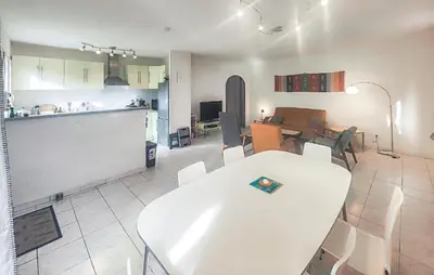 a kitchen and living room with a white table and chairs at Pause Nature Avec Piscine in Ferrières-Poussarou