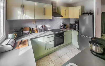 a kitchen with green cabinets and a stainless steel refrigerator at Pause Nature Avec Piscine in Ferrières-Poussarou