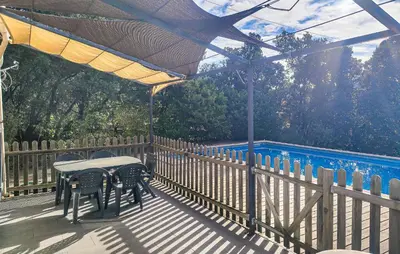 a table and chairs on a deck with a fence at Pause Nature Avec Piscine in Ferrières-Poussarou