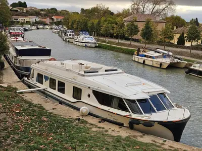 a boat is docked in a river with other boats at BATEAU NAVYLIS Croisière in Capestang