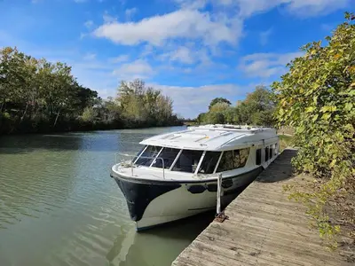 a boat is docked at a dock on a river at BATEAU NAVYLIS Croisière in Capestang