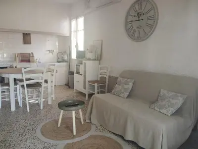 a living room with a couch and a clock on the wall at Appartement bord de mer in Port-la-Nouvelle