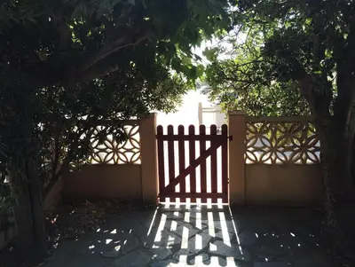 a gate in front of a fence with trees at Appartement bord de mer in Port-la-Nouvelle