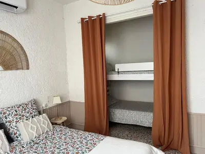 a bed with an orange curtain in a bedroom at Appartement bord de mer in Port-la-Nouvelle