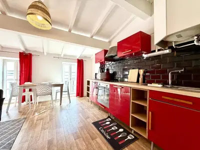 a kitchen with red cabinets and a dining table at L'Etoile Rouge - T2 Proche Gare et Centre Ville in Carcassonne