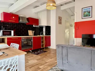 a kitchen with red cabinets and a table in a room at L'Etoile Rouge - T2 Proche Gare et Centre Ville in Carcassonne